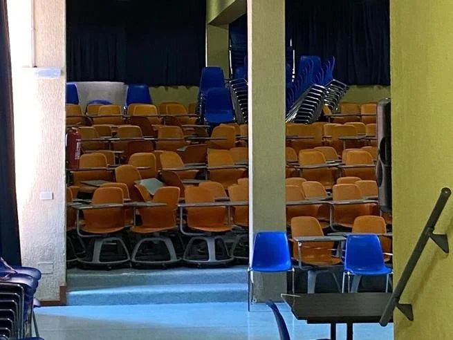 Scuola : Aula magna del Liceo Seneca piena di banchi a rotelle inutilizzati